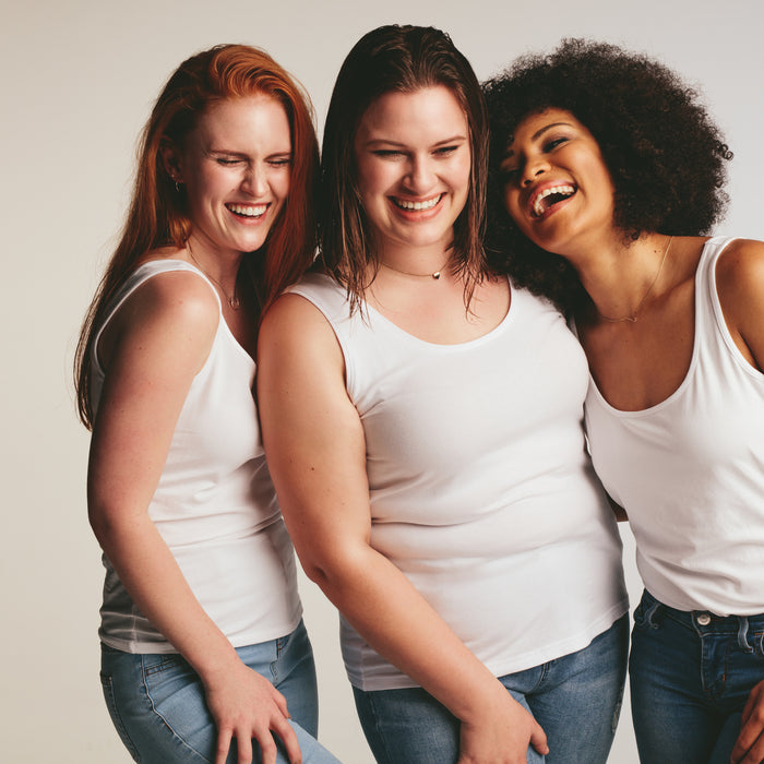 Diverse group of women laughing together on white background. Females in casuals looking happy together.