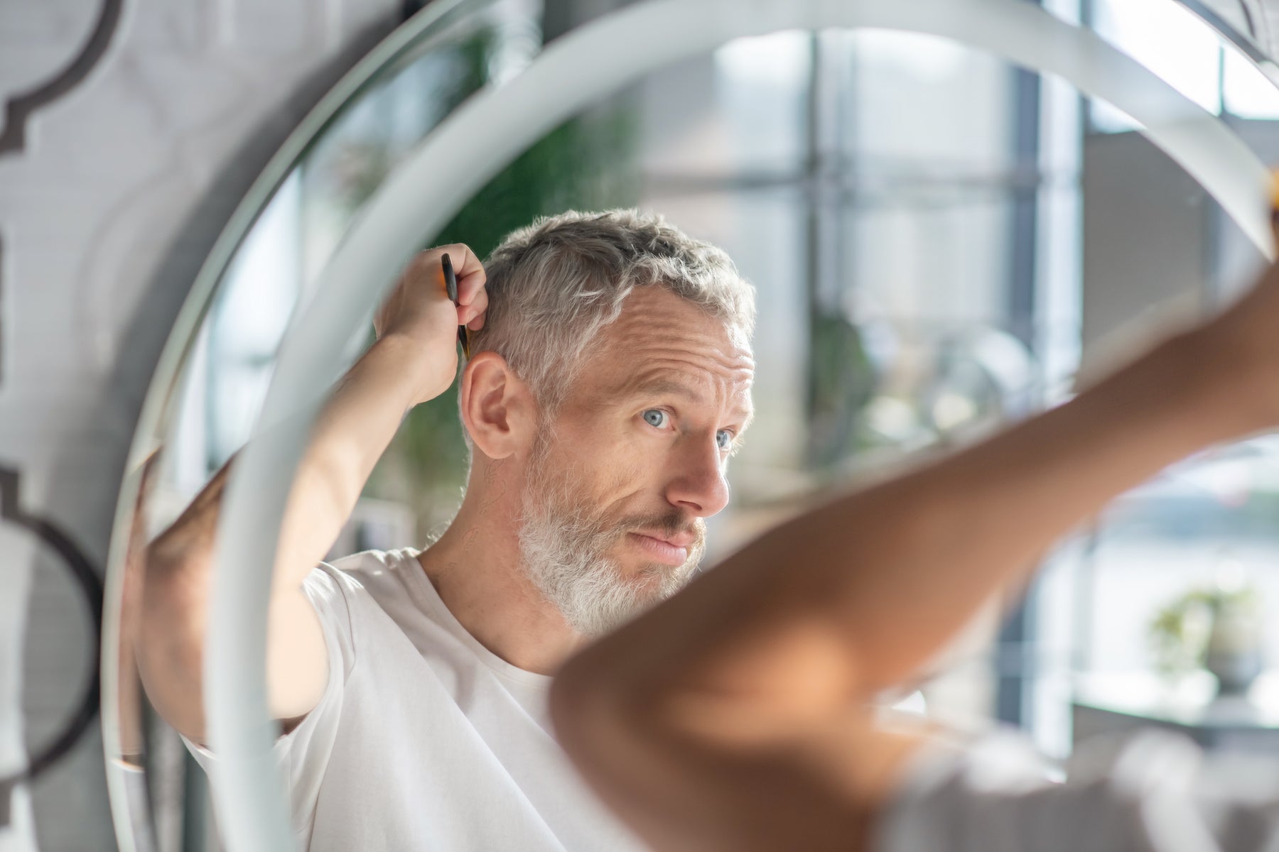 Creating a hairstyle. A man combing his hair in the morning